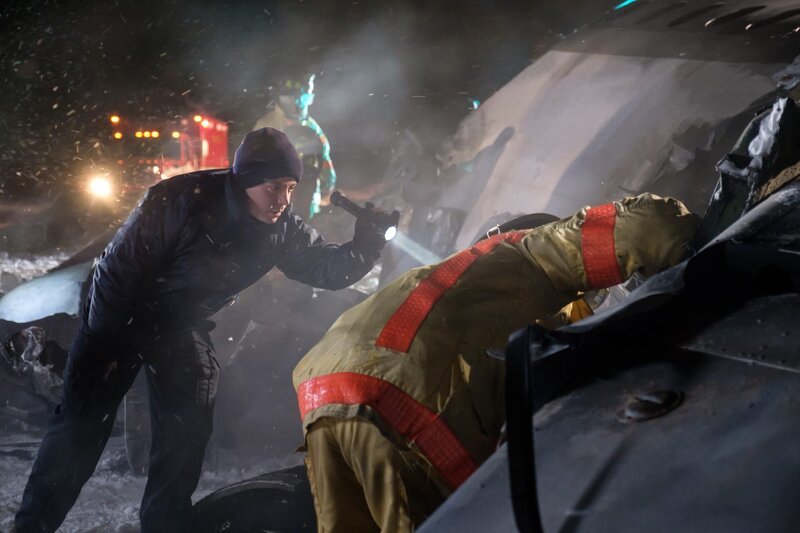 A rescuer (played by a background actor) shines a light into the crash site as a firefighter (played by a background actor) peers into the wreckage of Continental Airlines Flight 1713. – Bild: Darren Goldstein /​ Cineflix /​ Cineflix/​Darren Goldstein
