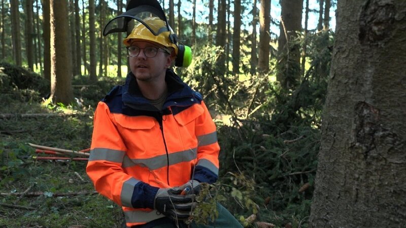 Dennis soll als zukünftiger Brandschützer lernen, einen Baum mit der Kettensäge zu fällen. – Bild: ZDF und Alex Glück./​Alex Glück