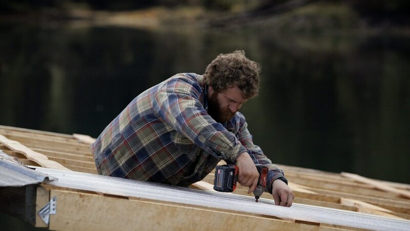 Oliver schraubt die Dacheindeckung seines Floßbaus an. (National Geographic) – Bild: National Geographic /​ National Geographic