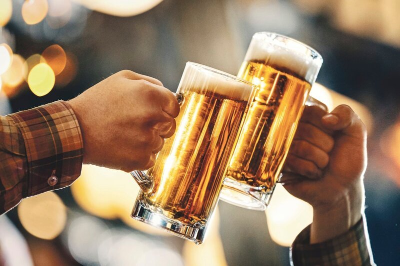Closeup side view of two men toast with draft beer in large mugs. – Bild: GettyImages