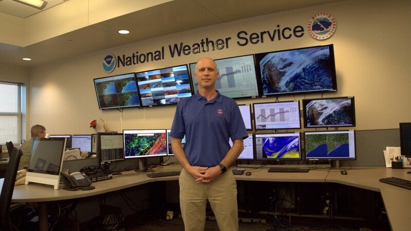 Im Büro des National Weather Service in Galveston steht der zuständige Meteorologe Jeffry Evans vor einer Reihe von Vorhersagebildschirmen. – Bild: Tom Kirkman /​ National Geographic/​Tom Kirkman /​ National Geographic