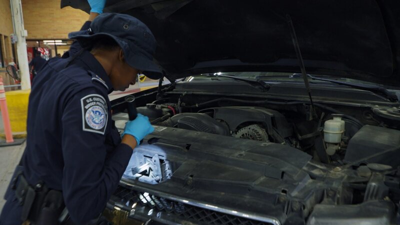 CBP-Beamter Thomas inspiziert mit einer Taschenlampe die Motorhaube des Fahrzeugs eines Passagiers am Einreisehafen von Hidalgo in Hidalgo, Texas. (National Geographic) – Bild: National Geographic /​ Disney