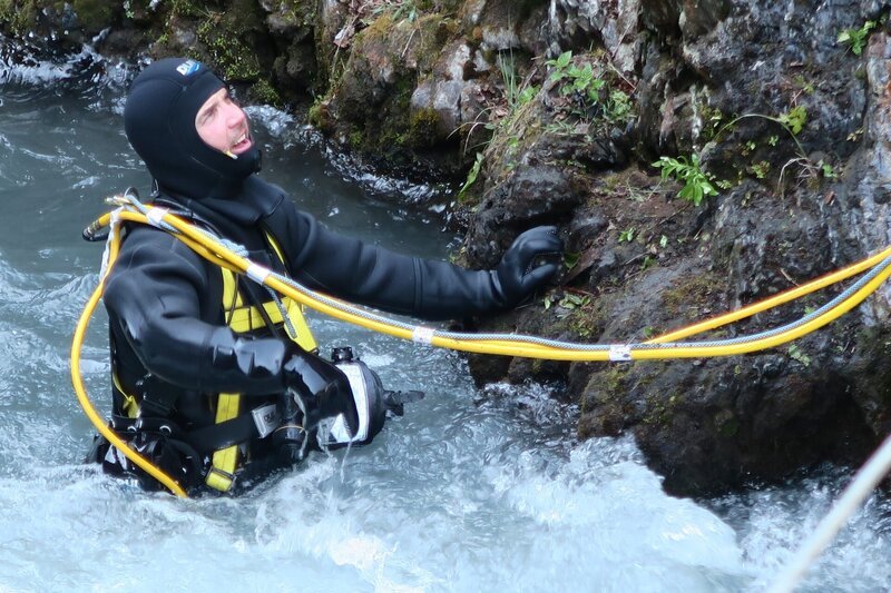 Dustin Hurt in full dive gear in shallow edge of creek. – Bild: Discovery Networks /​ Discovery Channel /​ Discovery Communications