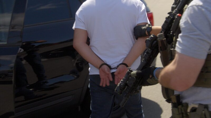 Ein Verdächtiger wird während eines HSI-Einsatzes in Orange County, Kalifornien, in Handschellen abgeführt. (National Geographic) – Bild: Disney