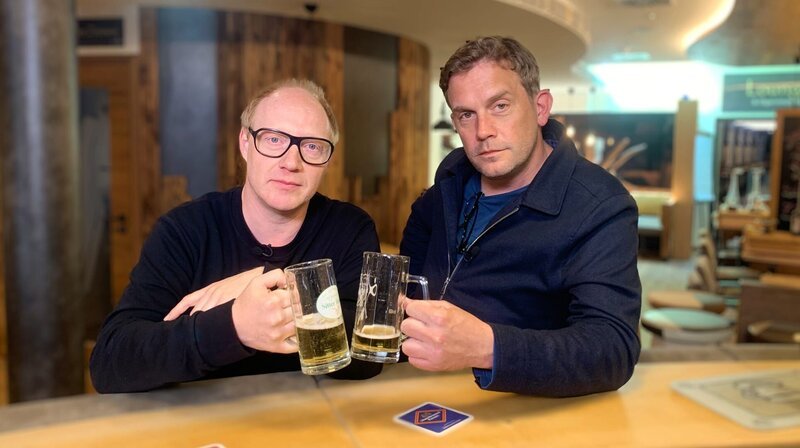 Von links: Simon Schwarz und Sebastian Bezzel trinken ein Bier an der Theke des Bierhotels. – Bild: BR/​strandgutmedia GmbH/​Benjamin Frank