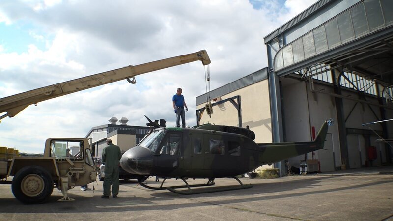 Michael Manousakis (l.) neben dem Militärhubschrauber Bell UH-1 Iroquois – Bild: Warner Bros. Discovery