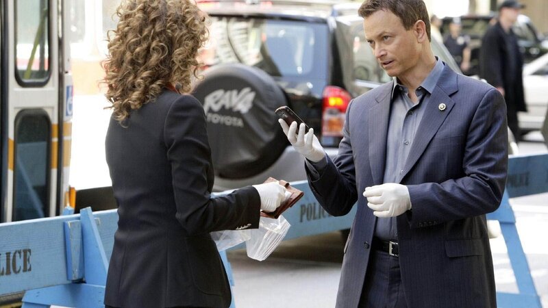 Die Detectives Bonasera (Melina Kanakaredes) und Taylor (Gary Sinise) stellen das Handy des Opfers sicher. Eine erfolgreiche Unternehmensberaterin wurde während eines Straßenfestes ermordet. – Bild: TVNOW /​ CBS