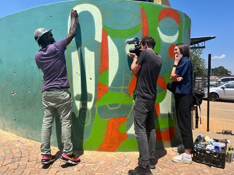 Das ZDF-Team bei Dreharbeiten mit Street-Art-Künstler Senzo Nhlapho im ärmlich geprägten Kliptown. – Bild: ZDF und Mfanasibili Nkosi.