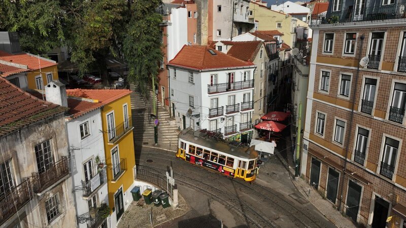 Die Straßenbahn E28 ist von oben zu sehen, wie sie sich auf ihrer kurvenreichen Strecke durch die Straßen im Zentrum von Lissabon, Portugal, einer Ecke nähert. (National Geographic/​Carlos Pinota) – Bild: National Geographic/​Carlos Pinota /​ National Geographic /​ Carlos Pinota