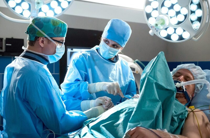Dr. Lea Peters (Anja Nejarri, M.) und Elias Bähr (Stefan Ruppe, l.) operieren den Patienten Jost Helmer (Andreas Anke, r.). – Bild: ARD/​Jens Ulrich Koch