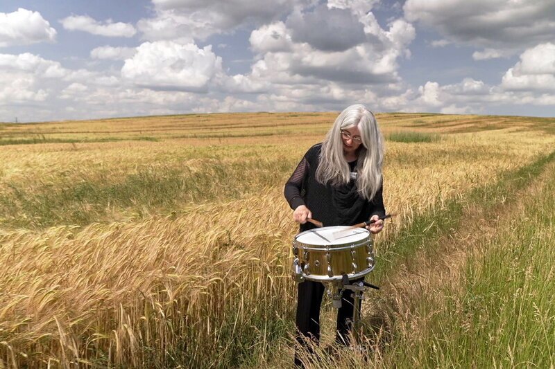 Signes Evelyn Glennie, hören mit dem ganzen Körper Evelyn Glennie spielt in einem Weizenfeld Snare Drum. SRF/RTS/ZED – Bild: SF1