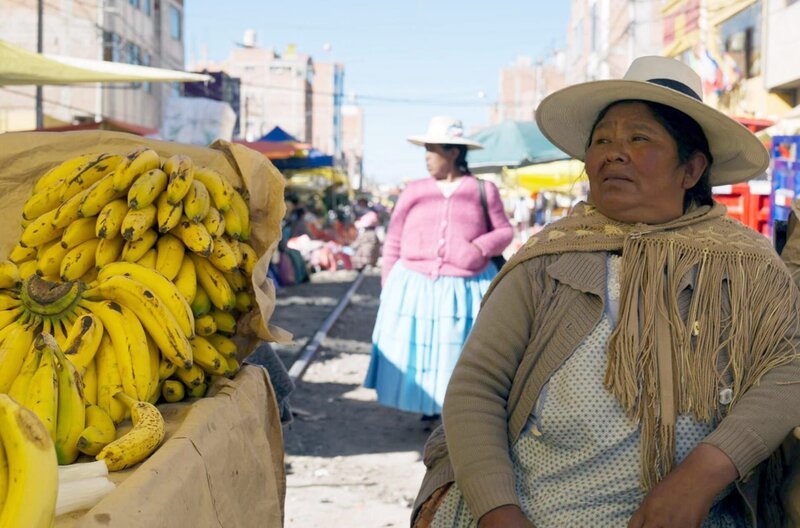 Eine Bananenhändlerin sitzt auf den Schienen in Puno: Die Durchfahrt jedes Zuges wird von einem vorausfahrenden Sicherheitsfahrzeug angekündigt, damit die Schienen geräumt werden. – Bild: Medea Film/​Lizeth Yarlequé /​ Eine Bananenhändlerin sitzt auf den Schienen in Puno: Die Durchfahrt jedes Zuges wird von einem vorausfahrenden Sicherheitsfahrzeug angekündigt, damit die Schienen geräumt werden.