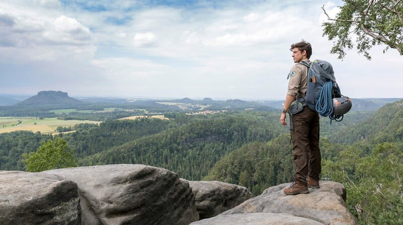 Ranger Jonas Waldek (Philipp Danne) an einer Felswand im Elbsandsteingebirge. – Bild: MDR/​ndF/​Tom Schulze