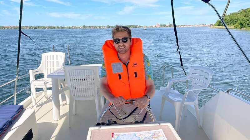 Johannes Zenglein am Steuer seines Charterboots. Fünf Tage lang ist er auf der Mecklenburgischen Seenplatte unterwegs. – Bild: SWR/​NDR/​Bavaria Entertainment GmbH