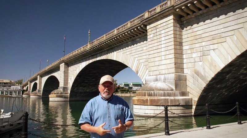 Jan Kassies aus Holland leitet das Touristenbüro in Lake Havasu City. Hinter ihm die alte London Bridge, gekauft von einem Amerikanischen Geschäftsmann und hier in der Wüstenstadt am Colorado wieder aufgebaut. – Bild: ZDF und MDR/​RBB/​José Luis Ocejo.