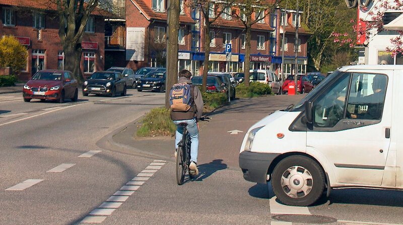 Ein Fahrradfahrer fährt knapp vor einem Transporter über die Straße. – Bild: NDR