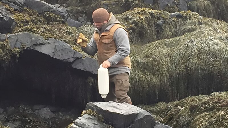 Bill McConnell on a rocky shore with a buoy and work gloves on Maine. – Bild: Discovery Communications