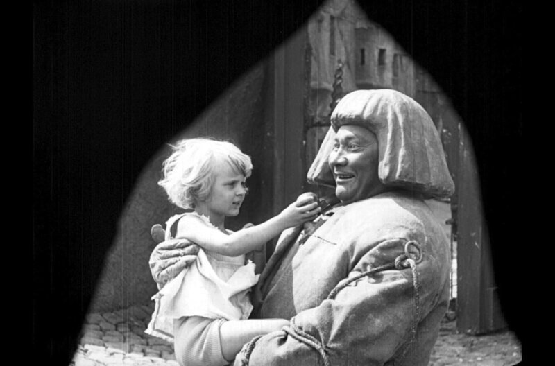 Das kleine Mädchen (Loni Nest) reicht dem Golem (Paul Wegener) den Versöhnungsapfel. – Bild: Filmmuseum München /​ © Filmmuseum München