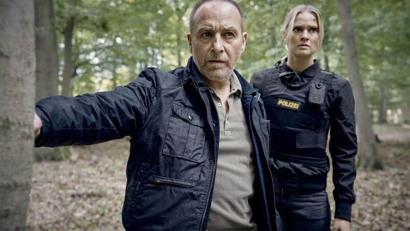 Semir (Erdogan Atalay) und Vicky (Pia Stutzenstein) verfolgen den Geiselgangster und finden eine Blutspur im Wald. – Bild: RTL /​ Guido Engels
