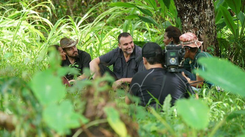 PAPUA NEW GUINEA- Michael sitting in lush greenery with camera man and translator talking to a local woman. (Photo credit: National Geographic/​Brian Mandle) – Bild: Copyright © The National Geographic Channel.
