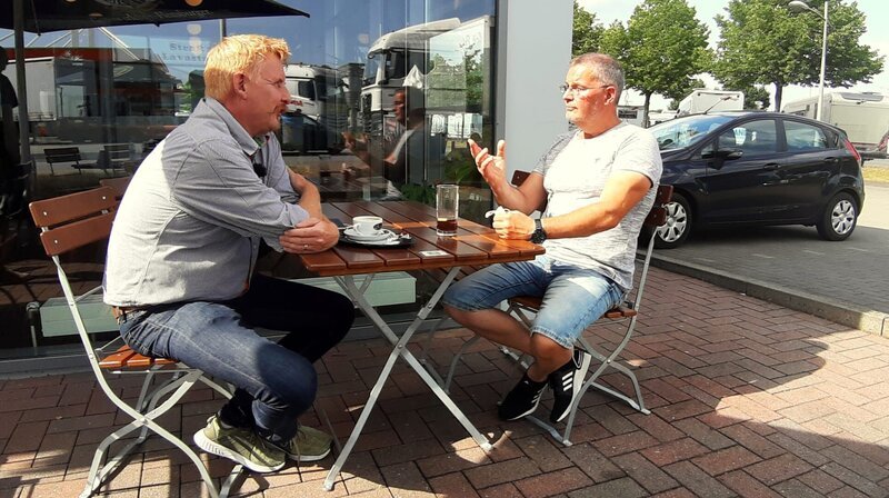 Plausch unter Autohofkollegen: Tankstellen-Chef Heiko Rasmussen und Wohnmobil-Experte Frank Niehoff gönnen sich eine kurze Pause. – Bild: NDR/​Produktion Clipart