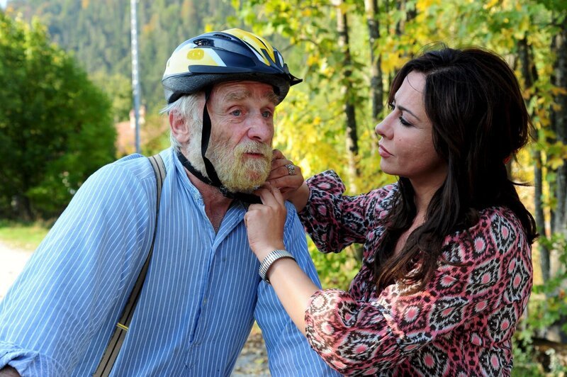 Dorfhelferin Katja Baumann (Simone Thomalla) setzt dem alten Senn Sepp (Peter Mitterrutzner) einen Fahrradhelm auf. – Bild: ZDF und Christiane Pausch