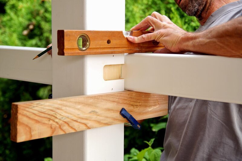 carpentry joints. Wood post, rabbet joint. Mounting the carport. carpenter using a spirit level to connect a spruce wooden beam for Carport outdoor construction. – Bild: Shutterstock /​ Shutterstock /​ Copyright (c) 2019 Mabeline72/​Shutterstock. No use without permission.