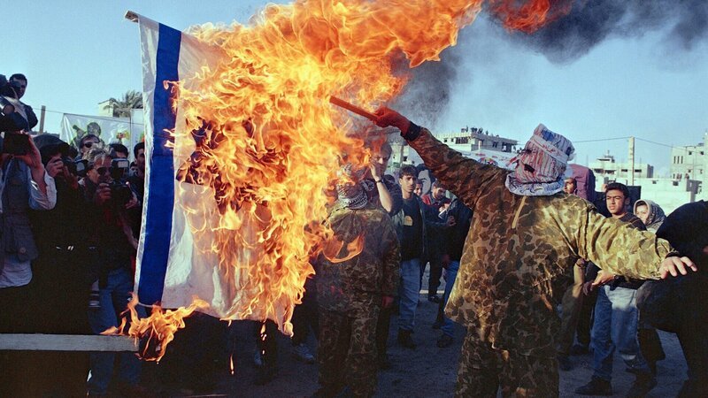 1994 in Gaza City:  Maskierte Islamische Aktivisten verbrennen einen israelische Flagge. – Bild: Nabil Judah