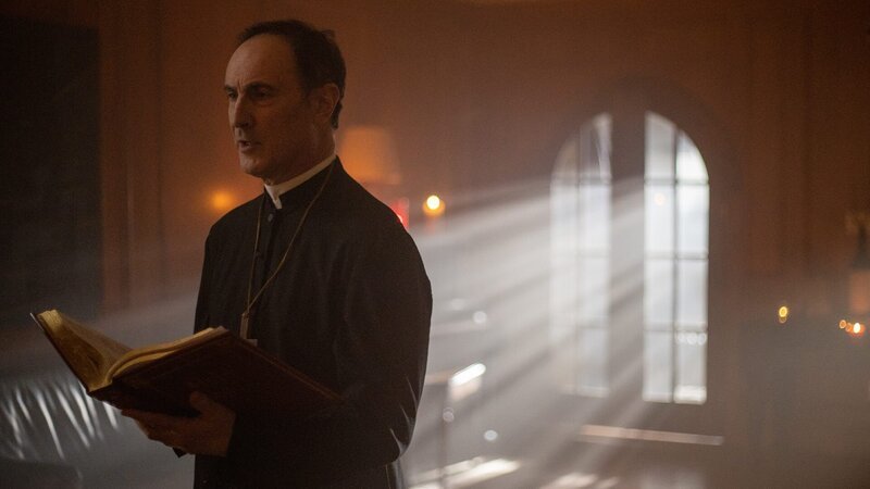 Der Priester liest aus dem Buch. – Bild: Warner Bros. Discovery