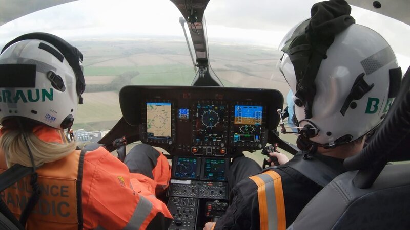 Rachel and Pilot Harry sitting in the font of the helicopter. – Bild: Warner Bros. Discovery