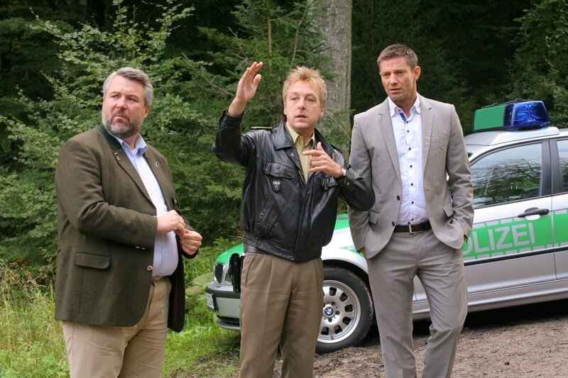 Als ein Forstbesitzer morgens tot in seinem Wald gefunden wird, ermitteln die Rosenheimer Kommissare Stadler (Dieter Fischer, l.), Hansen (Igor Jeftic, r.) und Polizist Mohr (Max Müller, M.). – Bild: ZDF /​ Christian A. Rieger