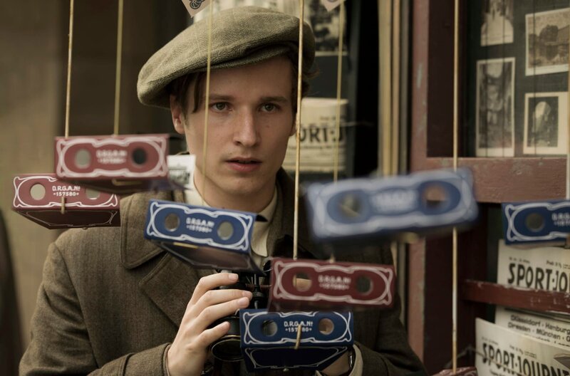Jänicke (Anton von Lucke) kann von den Lippen ablesen und observiert Verdächtige mit einem Fernglas. – Bild: ARD Degeto/​X-Filme/​Beta Film/​Sky Deutschland/​Frédéric Batier