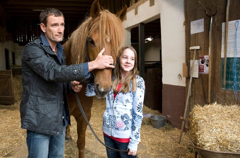 Tierarzt Dr. Philipp Hansen (Heikko Deutschmann) und Tochter Greta (Enya Elstner) haben das Pflegepferd Windrose verarztet. – Bild: SWR/​Maria Wiesler