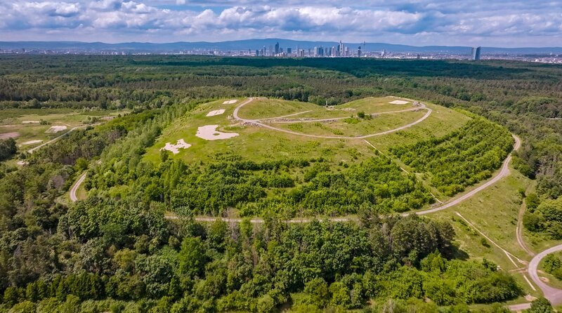 Begrünter Müllberg vor der Skyline von Frankfurt am Main. – Bild: BR/​Längengrad Filmproduktion