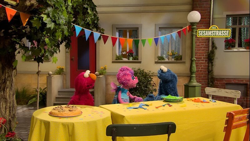 Elmo (l.) und Abby (m.) haben einen Kuchen gebacken, den Krümel (r.) ziemlich lecker findet. – Bild: NDR/​Sesame Workshop