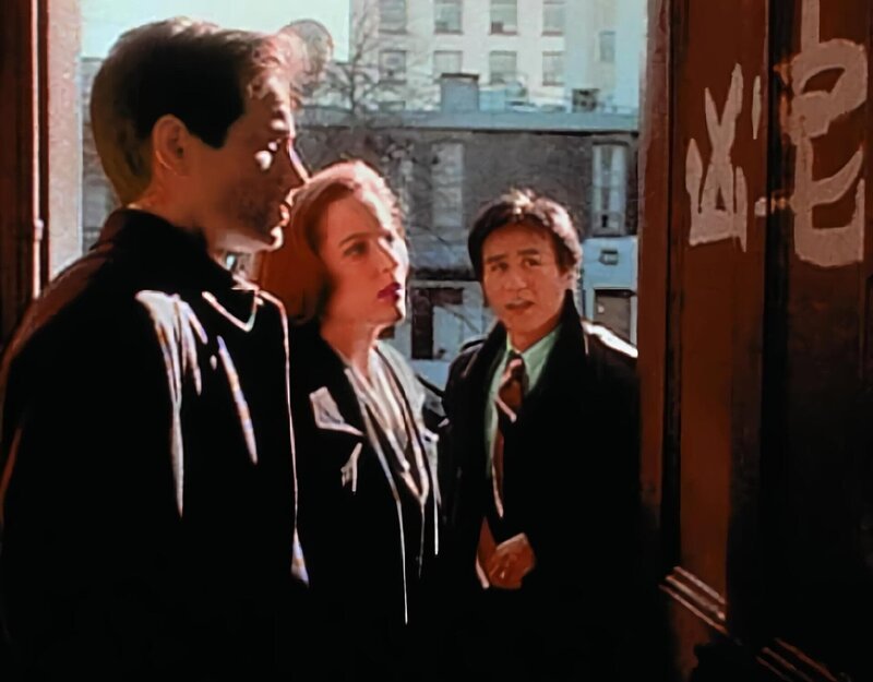 Obwohl Detective Glen Chao (B.D. Wong, r.) chinesischer Abstammung ist, kann er die Schriftzeichen an der Wohnungstür eines Mordopfers für Mulder (David Duchovny, l.) und Scully (Gillian Anderson, M.) nicht übersetzen. – Bild: ProSieben MAXX