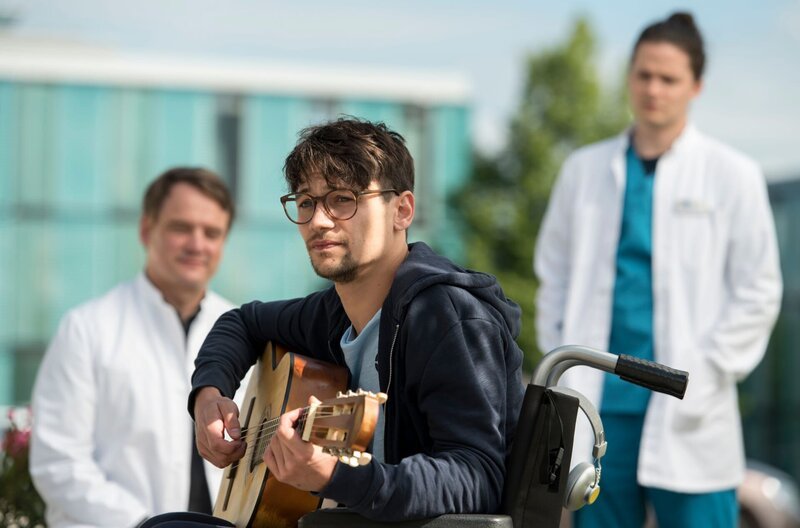 Malte, den Marc wegen einer Krebsbehandlung bereits kennt, kommt mit einer Sprunggelenksverletzung ins Klinikum. V.l.n.r. Marc Lindner (Christian Beermann), Malte Wenzel (Doga Gürer), Tom Zondek (Tilman Pörzgen) – Bild: ARD/​Jens Ulrich Koch/​Jens Ulrich Koch