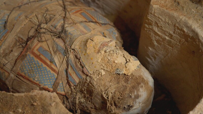 Eine frisch entdeckte, eingewickelte Mumie liegt in ihrem Sarkophag in der Nekropole von Oxyrhynchus in Ägypten. Archäologen versuchen, den altägyptischen Glauben an das Leben nach dem Tod zu entschlüsseln. Verborgene Gräber und ein versiegelter Sarkophag geben ihre Geheimnisse preis. (Windfall Films) – Bild: Windfall Films /​ Windfall Films
