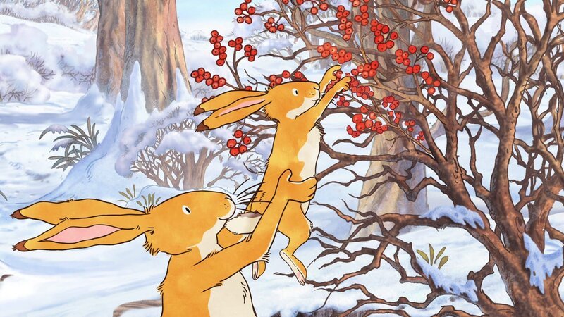 Der große braune Hase hebt den kleinen braunen Hasen hoch, damit er Beeren vom Strauch pflücken kann. – Bild: KiKA/​SLR Productions Australia Pty.Ltd./​Scrawl Studios Pte Ltd./​hr/​ARD