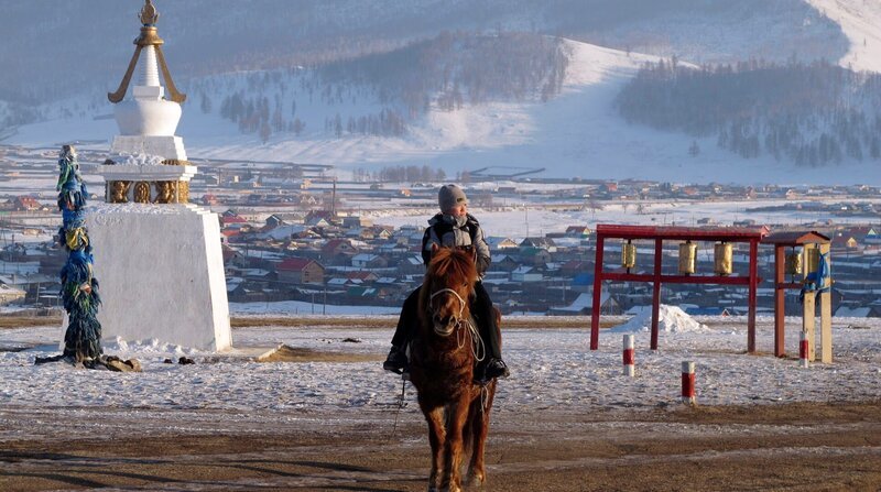 Der Nomadenjunge Tuguldur reitet nach der Schule nach Hause. Im Hintergrund der Schulort Tunkhel, 200 Kilometer nördlich von der Hauptstadt Ulan Bator. – Bild: ZDF und MDR/​Karsten Scheuren.
