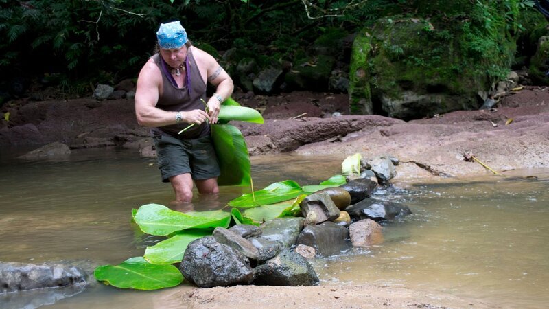 Cody Lundin with holding log above river. – Bild: Discovery Communications