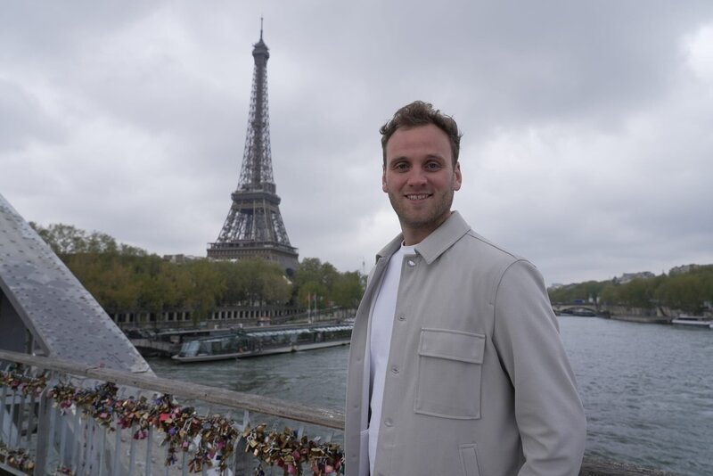 Leon Windscheid auf der Liebesschlösserbrücke Pont des Arts. Im Hintergrund das Wahrzeichen von Paris – der Eifelturm. – Bild: ZDF und Yannick Rouault./​Yannick Rouault
