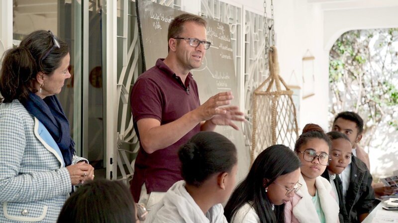 Geschäftsführer David Depenau stellt sein Unternehmen, den Ferien- und Freizeitpark Weissenhäuser Strand, in Madagaskar vor. Er hofft, junge Menschen, die hier deutsch lernen, für eine Ausbildung in Schleswig-Holstein zu begeistern. David Depenau ist auf der ganzen Welt unterwegs, um Arbeitskräfte anzuwerben. Insbesondere die Gastronomie leidet unter Arbeitskräftemangel. – Bild: NDR/Laura Borchardt Geschäftsführer David Depenau stellt sein Unternehmen, den Ferien- und Freizeitpark Weissenhäuser Strand, in Madagaskar vor. Er hofft, junge Menschen, die hier deutsch lernen, für eine Ausbildung in Schleswig-Holstein zu begeistern. David Depenau ist auf der ganzen Welt unterwegs, um Arbeitskräfte anzuwerben. Insbesondere die Gastronomie leidet unter Arbeitskräftemangel. – Bild: NDR/Laura Borchardt