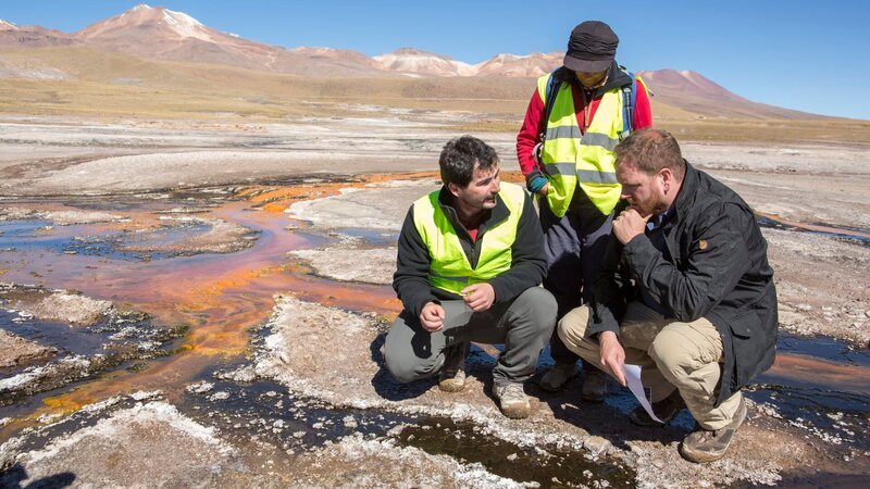 El Tatio Geysirfeld, Atacama-Wüste, Chile: Gastgeber Josh Gates (r.) und die Wissenschaftler Carolina Munoz-Saez (PHD Earth & Planetary Science, m.) und J.R Stok (PHD Geological Sciences, Marsgeologe, l.) diskutieren über die Unterschiede zwischen den Geysiren auf der Erde und dem Mars im El Tatio Geysirfeld in den chilenischen Anden in der Atacama-Wüste, der trockensten nichtpolaren Wüste der Welt. – Bild: Gilles Mingasson /​ 36047_TETH_101H_0095 /​ © 2017, The Travel Channel, L.L.C. All Rights Reserved.
