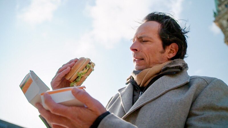 Moderator Jo Hiller testet einen Burger. – Bild: ORF/One Gate Moderator Jo Hiller testet einen Burger. – Bild: ORF/One Gate