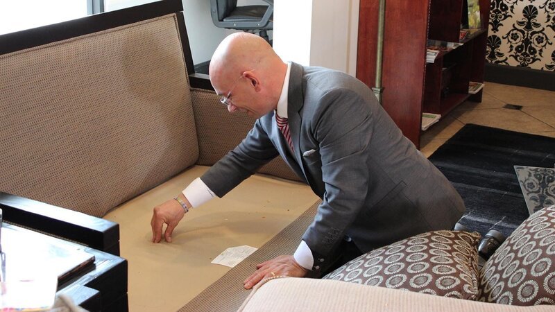 Anthony inspects a couch in the lobby of the Curve Hotel, as seen on Travel Channel’s Hotel Impossible. – Bild: The Travel Channel, L.L.C.
