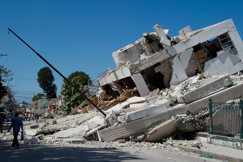 Ein zerstörtes Gebäude ist am 13. Januar 2010 in Port-au-Prince, Haiti, zu sehen. Unmengen von Rettern und Hilfsgütern gingen nach Haiti, als Regierungen und Hilfsorganisationen nach einem starken Erdbeben, das möglicherweise Tausende Menschen getötet hat, eine massive Hilfsaktion starteten. US-Präsident Barack Obama ordnete schnelle und aggressive Rettungsmaßnahmen für die USA an, während die Europäische Union ihre Krisensysteme aktivierte und das Rote Kreuz und die Vereinten Nationen Hilfsgelder und Hilfsgüter für die mittellose Nation bereitstellten. Ein Großteil von Port-au-Prince wurde durch das Beben von 7,0 am 12. Januar in Schutt und Asche gelegt, aber der Flughafen war betriebsbereit und ebnete den Weg für internationale Hilfeleistungen, die sowohl auf dem Luftweg als auch auf dem Seeweg eingesetzt werden konnten. – Bild: Frederic Dupoux /​ Voltage TV /​ Getty Images South America /​ Getty Images