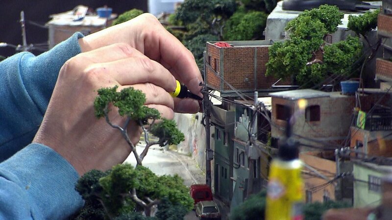 Ein Modellbauer verlegt Stromleitungen in der Favela des Rio-Modells. – Bild: RTL /​ SPIEGEL TV