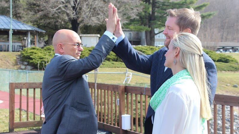 Host Anthony Melchiorri high-fives owner Shaun Lyons on the pool patio of Water Gap Country Club while Julie Lyons looks on, as seen on Travel Channel’s Hotel Impossible. – Bild: The Travel Channel, L.L.C.
