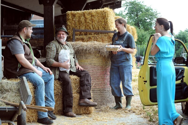 Vor dem Voglhof machen Sverin, Stadlbauer und Sophia eine kleine Brotzeit. Von links: Severin (Andi Gießer), Stadlbauer (Andreas Geiss), Sophia (Patricia Freund), Katharina (Carina Dengler). – Bild: BR/​Marco Orlando Pichler